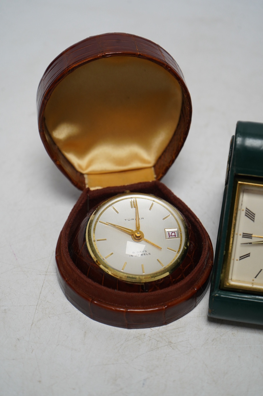 A Turler crocodile cased travelling alarm timepiece and another in green leather. Condition - green case a little scuffed, both wind and are currently ticking but not guaranteed